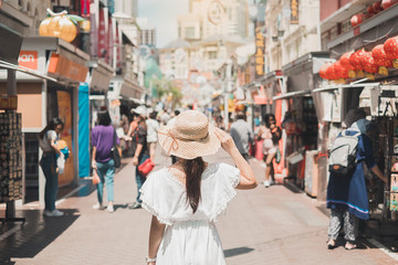 Young Woman traveling with white dress and hat, happy Asian traveler walking at Chinatown street market in Singapore. landmark and popular for tourist attractions. Southeast Asia Travel concept - obrazy, fototapety, plakaty