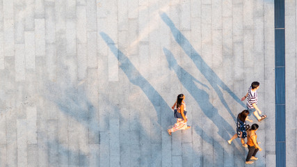 group of people walk on across the pedestrian concrete landscape in the city street (Aerial top...