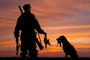 Poster hunter and his dog with prey at sunset © rodimovpavel