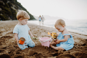 Two toddler children playing on sand beach on summer holiday. © Halfpoint