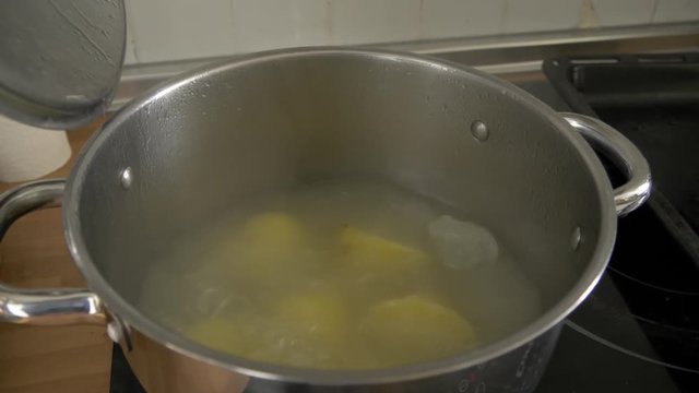 opening the top of a pot with boiling potatoes