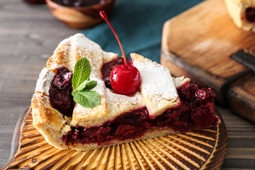 Board with slice of tasty cherry pie on table, closeup
