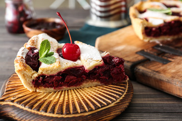 Board with slice of tasty cherry pie on wooden table