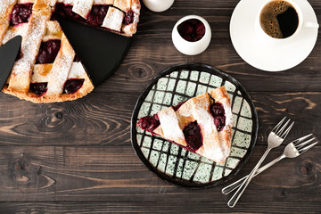 Tasty cherry pie with coffee on wooden table