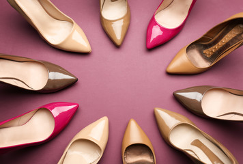 Different stylish high heeled shoes on color background