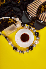 Fashion feminine blogger concept. Minimal set of women accessories with cup of coffee on yellow background. Still life perfume, jewellery, shoes, lace dress. copy space for text. Flat lay