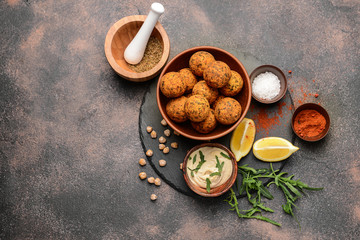 Bowl with tasty falafel balls and sauce on grey background