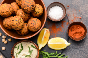 Bowl with tasty falafel balls and sauce on grey background
