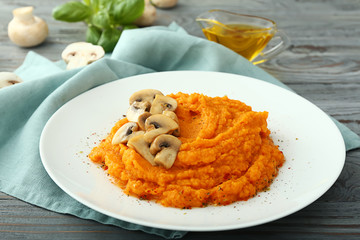Plate with mashed sweet potato and mushrooms on wooden background