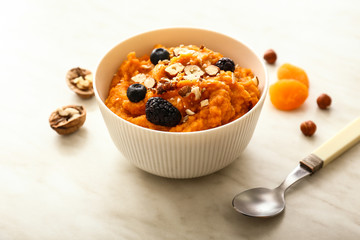 Bowl with mashed sweet potato, nuts and berries on table