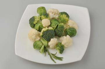 Different green vegetables on the plate gray background