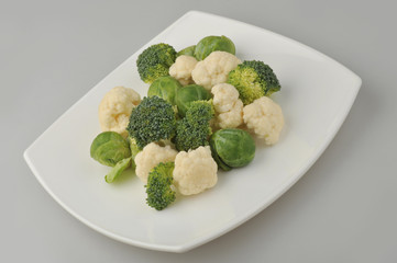 Different green vegetables on the plate gray background