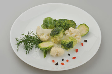 Different green vegetables on the plate gray background