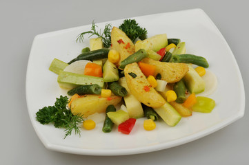 Different green vegetables on the plate gray background