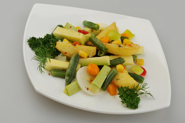 Different green vegetables on the plate gray background