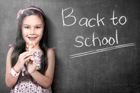 Asian Student Girl Standing And Holding Candy With Blackboard Background