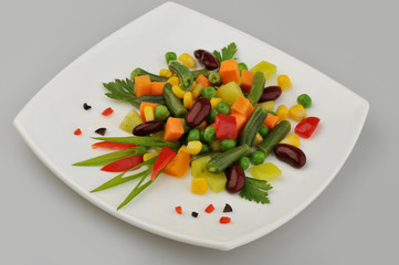 Different green vegetables on the plate gray background