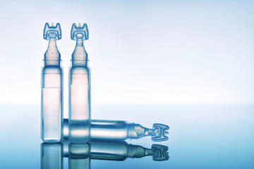 Lubricant eye drops in plastic pipettes blue background close up