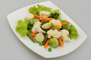 Different green vegetables on the plate gray background