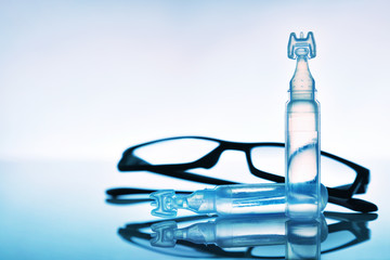 Lubricant eye drops with eye glasses and blue background composition