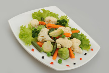 Different green vegetables on the plate gray background