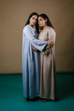 Portrait of two young Muslim Malay women sisters hugging and embracing one another. They are wearing traditional Baju Kurung dresses for Raya and are both beautiful, young and elegant.