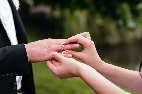The groom dresses the bride's wedding ring on hand.