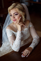 Fototapeta premium Portrait of a cute bride with a bouquet of roses indoor.Pretty happy bride in luxury dress in restaurant.young happy smiling bride holding bouquet of flowers.