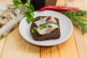 Open sandwich with pickled herring among ingredients for its preparation