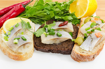 Different open sandwiches with pickled herring fillet close-up