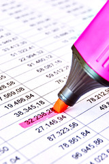 Red pink marker on a sheet of paper with printed financial numerical data table and marked numbers. Concept for accounting, budget, profit, tax and financial review. Vertical with selective focus