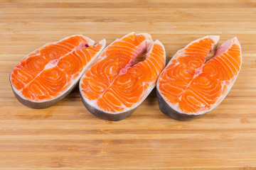 Uncooked steaks of arctic char on the wooden cutting board