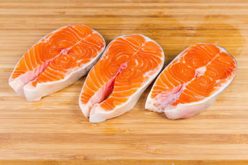 Uncooked steaks of arctic char on the wooden cutting board