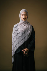 Studio portrait of a tall, slim, beautiful and elegant Middle Eastern Muslim woman in a black dress...