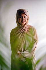 Portrait of a beautiful and attractive Malay Asian Muslim woman in a hijab head scarf standing by...