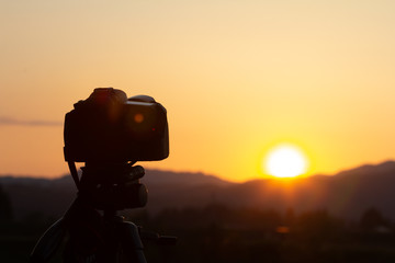 デジタル一眼レフカメラで美しい夕日を撮影している - obrazy, fototapety, plakaty