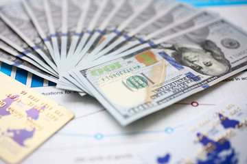 Big amount of US currency on financial statistics graphs closeup