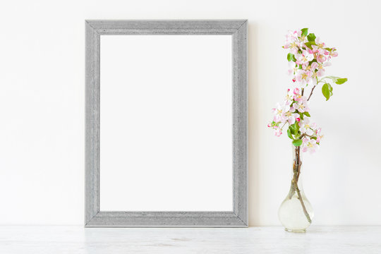Fresh branches of pink white apple blossoms in glass vase on table at light gray wall. Empty place for inspirational, emotional, sentimental text, lovely quote or sayings in frame. Front view. 