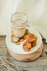 Flourless gluten free peanut butter, oatmeal and date with a glass of milk on a wooden background. Copy space.