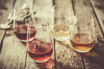 WIne tasting concept - red, rose, white and orange wine in glasses on wood background