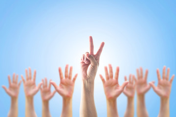 Leader's two fingers victory sign among blur hands crowd group for World participation, leadership, volunteer concept.