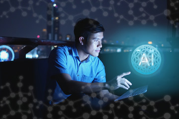 Businessman stand on roof top using laptop with hold the (AI)Artificial intelligence hologram,smart city and network connect concept