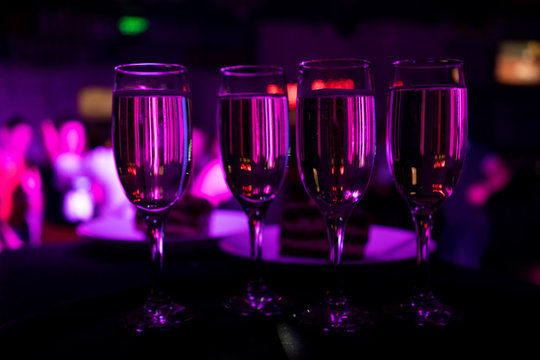 champagne glasses in a nightclub with violet lighting
