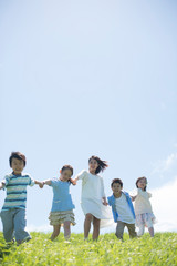 草原で手をつなぐ小学生と先生