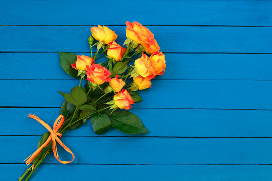 Background of a bouquet of beautiful fresh vivid orange roses tinged with red for celebrating an anniversary, birthday or Mothers Day