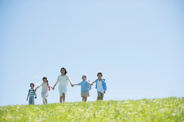 草原で手をつなぐ小学生と先生