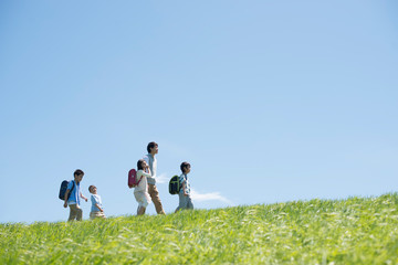草原を歩く小学生と先生