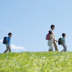 草原を歩く小学生と先生