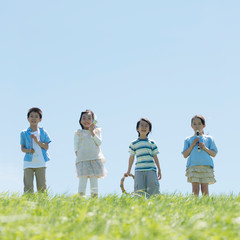 草原で楽器を持ち微笑む小学生