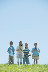 Obraz premium 草原で楽器を持ち微笑む小学生